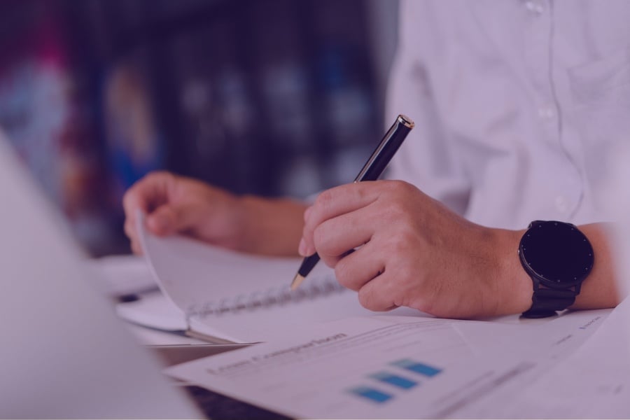 Person browsing through a report and taking notes.